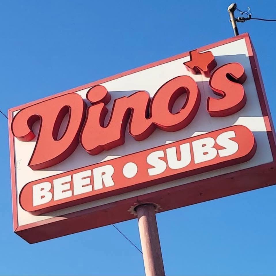 The vintage red Dino's Beer and Subs roadside sign against a blue sky